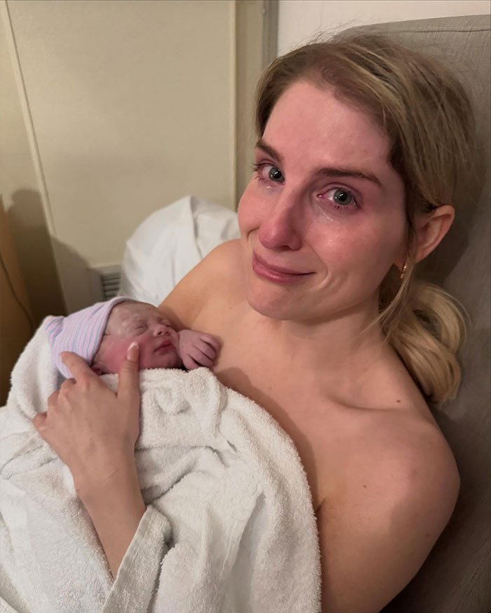 Meghan Trainor holding her newborn baby, emotional and smiling, highlighting surrogate journey and motherhood moments.