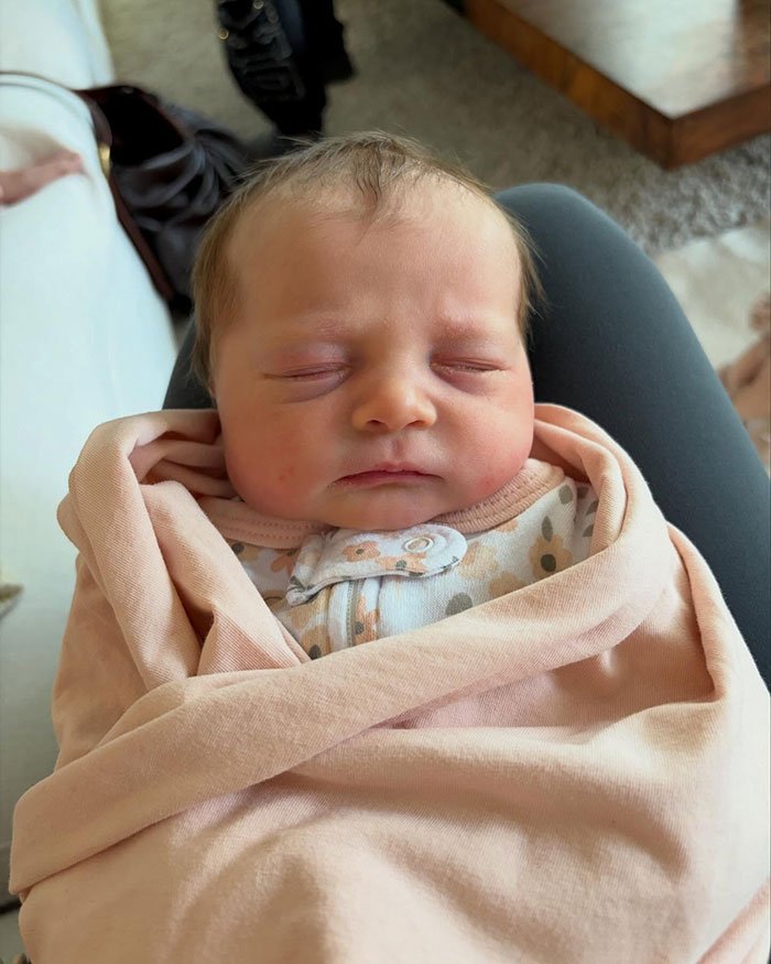Newborn baby peacefully sleeping, wrapped in a pink blanket, reflecting Meghan Trainor surrogate baby news.