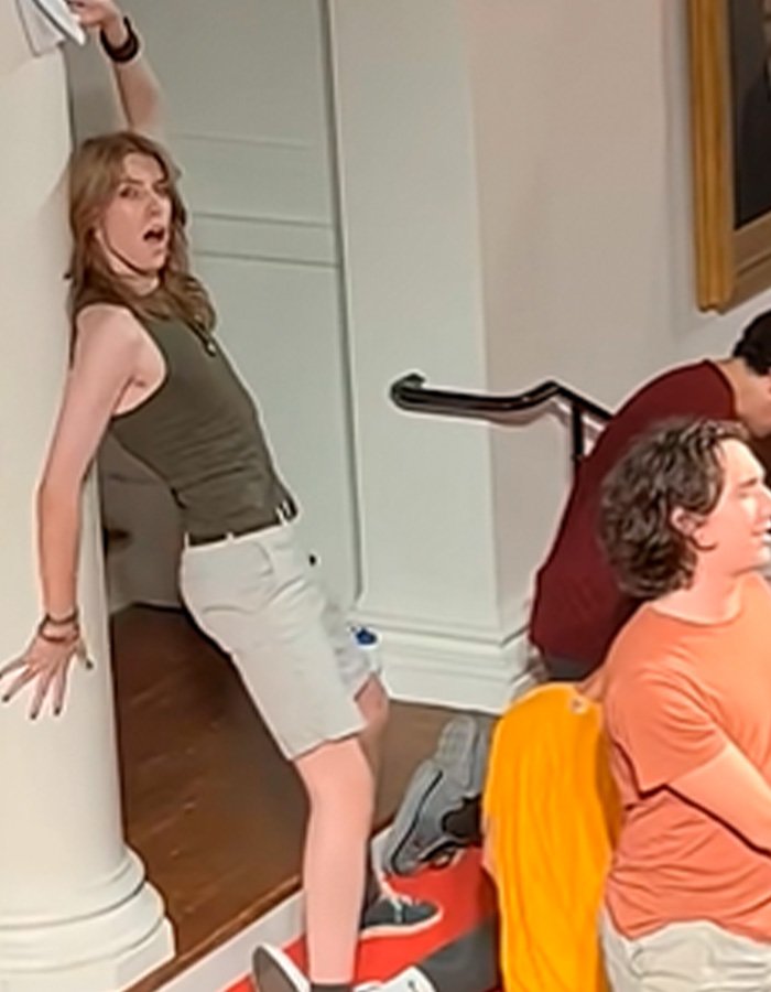 Young person in casual summer clothes leaning against a column during Amherst College raunchy orientation event backlash.