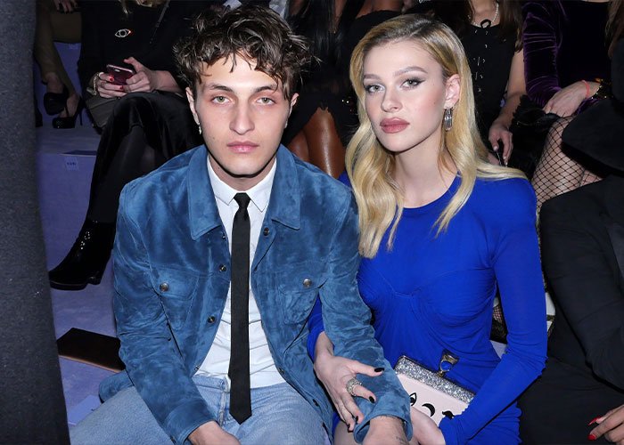Young couple seated at an event, highlighting sister of Nicola Peltz's ex amid Brooklyn Beckham’s scathing rant.
