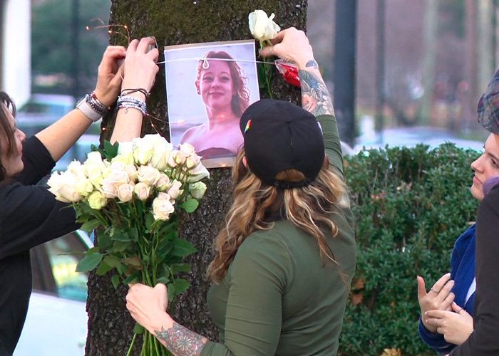 People placing flowers and a photo on a tree during a memorial as autopsy reveals harrowing details of Renee Good’s final moments