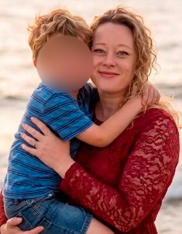 Woman in a red lace dress holding child by the ocean, related to autopsy released by Renee Good’s family details.