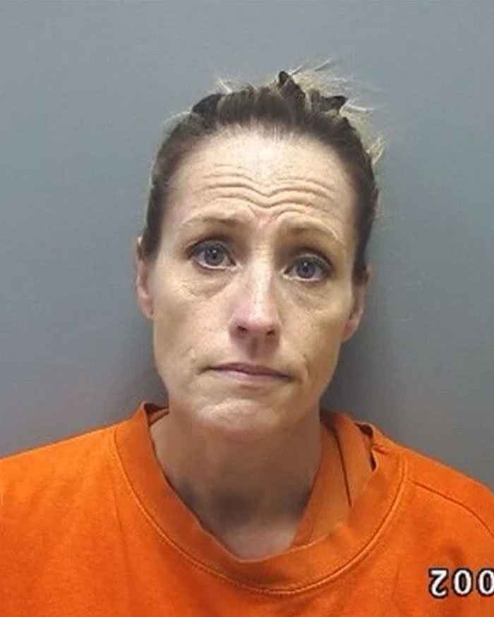Mugshot of a woman wearing an orange shirt, linked to Walmart theft scheme using stacking method over months.