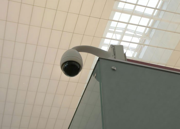 Surveillance camera mounted on ceiling inside a store, monitoring for theft and security using stacking method tactics.