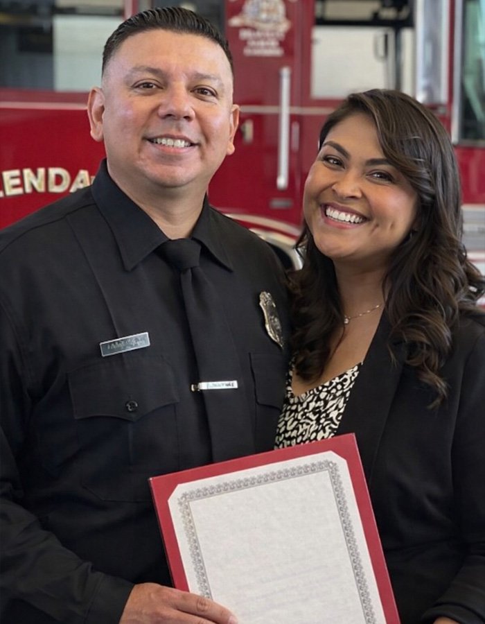 Smiling couple posing indoors, woman holding a framed document, highlighted by teacher’s life affair diary discovery keywords.