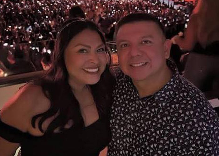 Couple smiling at a crowded evening event, highlighting the emotional impact of the teacher’s life and affair discovery.