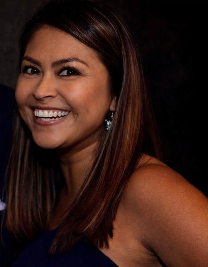Smiling woman with brown hair and earrings in a dark setting illustrating teacher’s life ends after diary affair discovery.