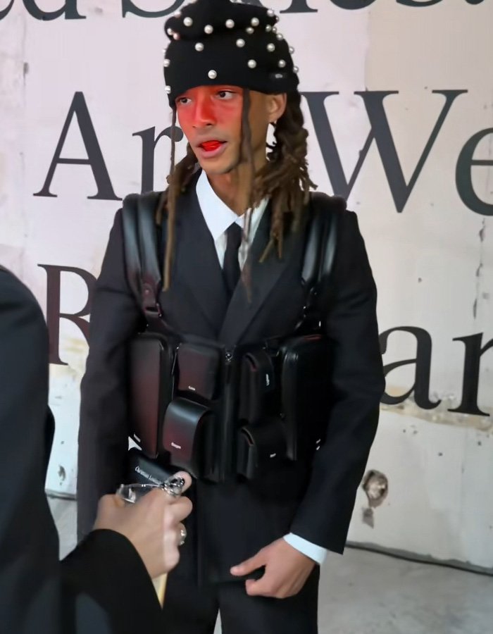 Fashion influencer wearing a pearl-studded hat and multiple black pouches in a bold streetwear look inspired by Black Brooklyn Beckham style