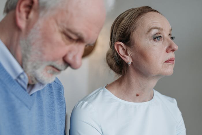 A distressed middle-aged couple in a tense moment reflecting conflict over in-laws refusing to help with childcare.