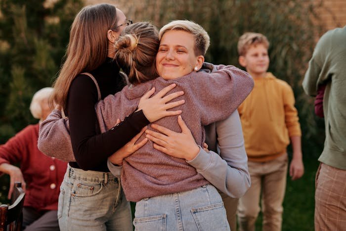 Woman sharing a warm group hug outdoors with multiple family members, highlighting unique parent relationships.