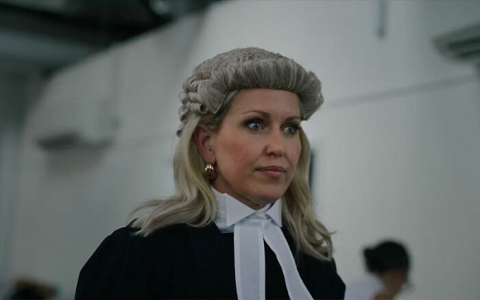 Amber Heard portraying a lawyer in a documentary scene revisiting defamation suits and the Depp trial.