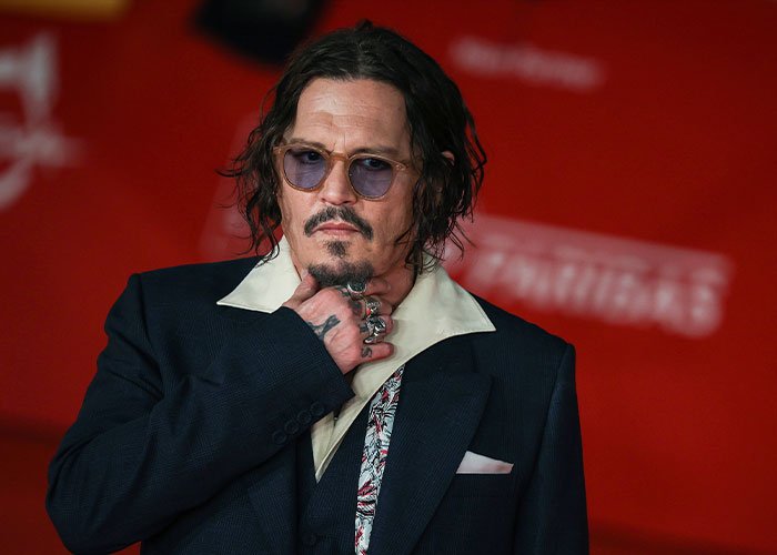 Johnny Depp wearing sunglasses and a dark suit at a public event amid Amber Heard defamation suits and Depp trial coverage.