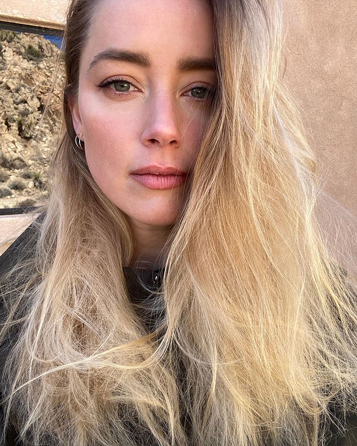 Amber Heard close-up portrait with long blonde hair outdoors, related to defamation suits and Depp trial documentary news.