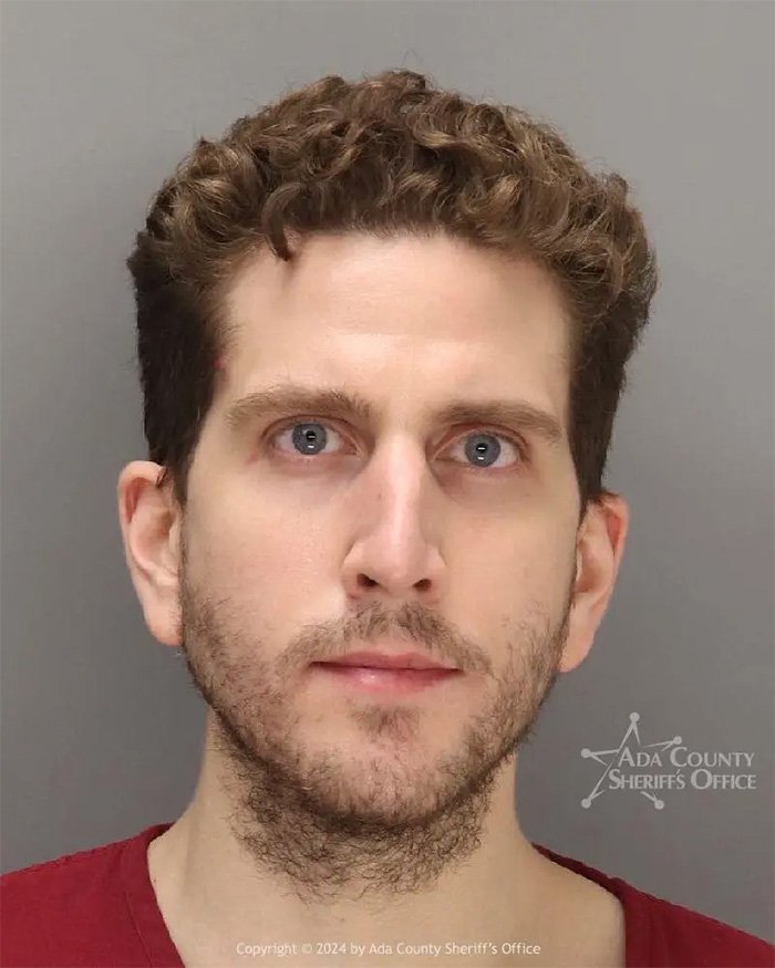 Mugshot of Bryan Kohberger with curly hair and beard, related to autopsy reports on his victims' final moments.