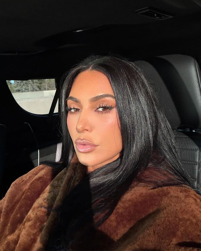 Kim Kardashian taking a selfie in a car wearing a brown fur coat, related to parenting controversy and viral livestream incident.