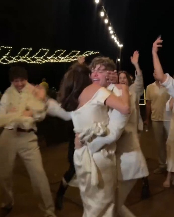 Groom’s mom dancing wildly at a wedding celebration with guests under string lights amid Beckham family fallout.