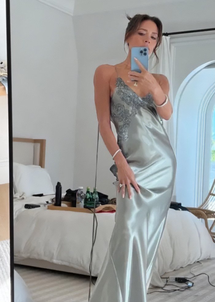 Victoria Beckham taking a mirror selfie in a silver dress amid Beckham family fallout and viral wedding dance news.