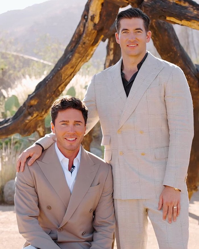 Two men dressed in suits posing outdoors with natural scenic background in a groom’s mom wedding dance viral context.