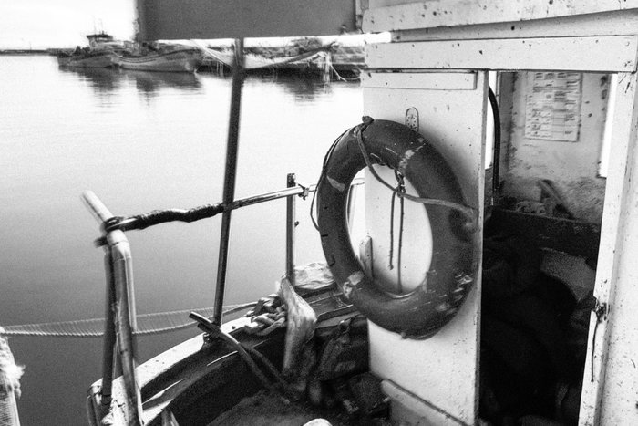 Lifebuoy hanging on a boat docked at calm water, symbolizing SOS code in rescue missions and maritime safety.