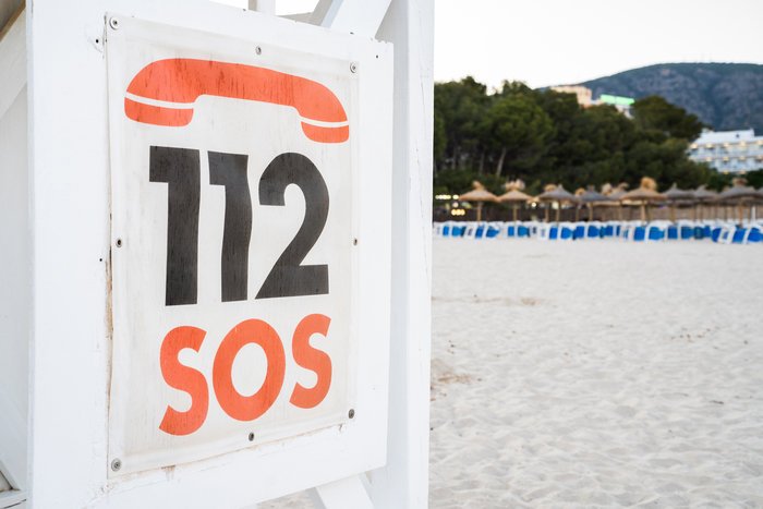 SOS emergency sign with 112 number on a beach, symbolizing rescue missions and urgent help communication.