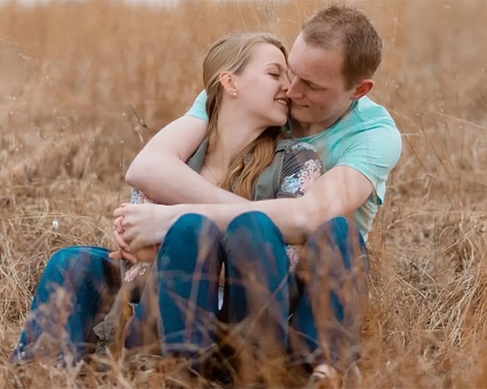 Young couple embracing in a dry field, unrelated to man admitting horrific charges over pregnant sister’s homicide.