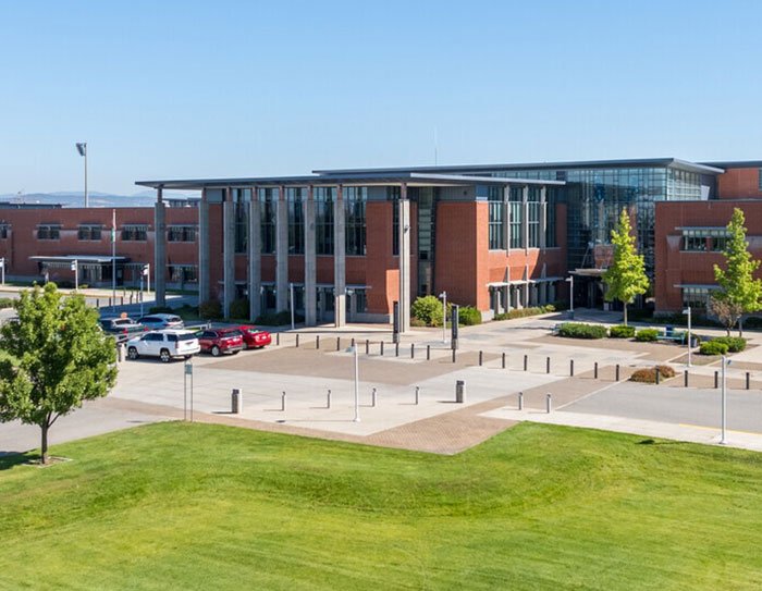 Modern school building exterior with cars parked outside, related to bold texts from teacher to student discussions.