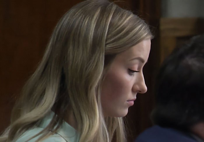 Young woman with blonde hair listening attentively during a serious discussion about teacher to student texts after intimate encounter.