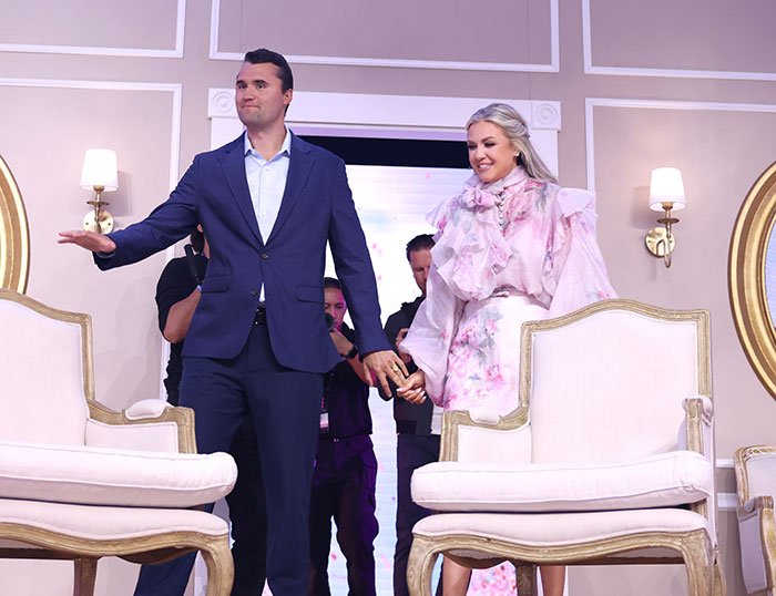 Erika Kirk smiling and holding hands with a man on stage amid backlash following leaked clip and explosive audio.