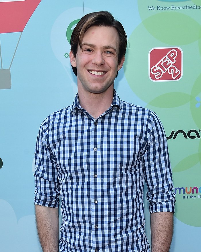 Young man in blue checkered shirt smiling at an event, related to Little Rascals star and Catholic extremist news.