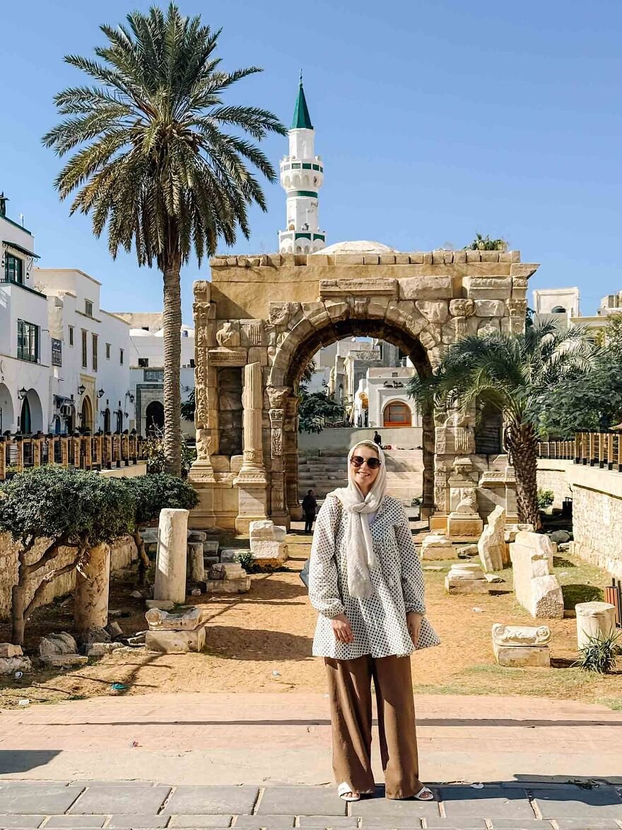 Woman standing near ancient stone arch with palm trees, symbolizing 15 nations setting new global standard for paid leave.