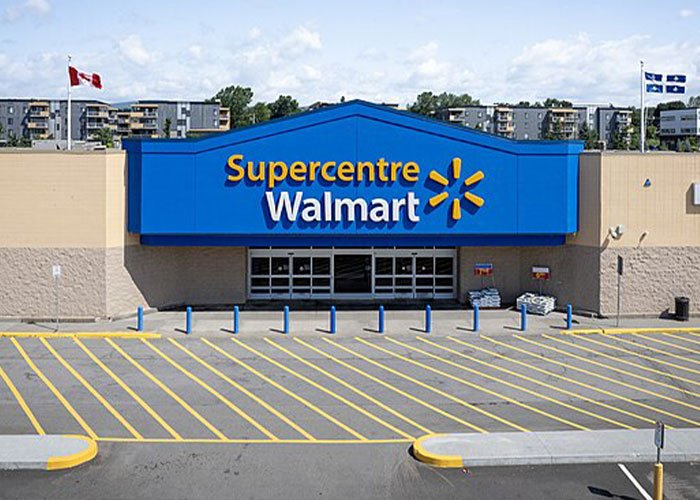 Walmart Supercentre entrance with empty parking lot under a clear sky during daytime, related to theft scheme news.
