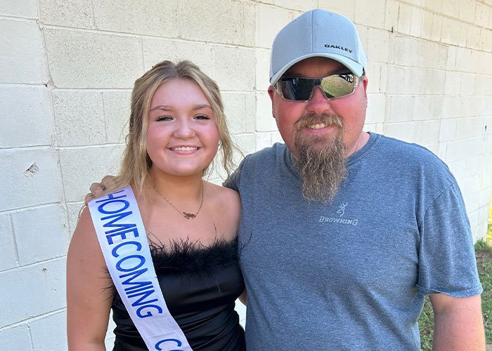 Father and teenage daughter smiling together outside, highlighting family impact of pregnancy involving young siblings.