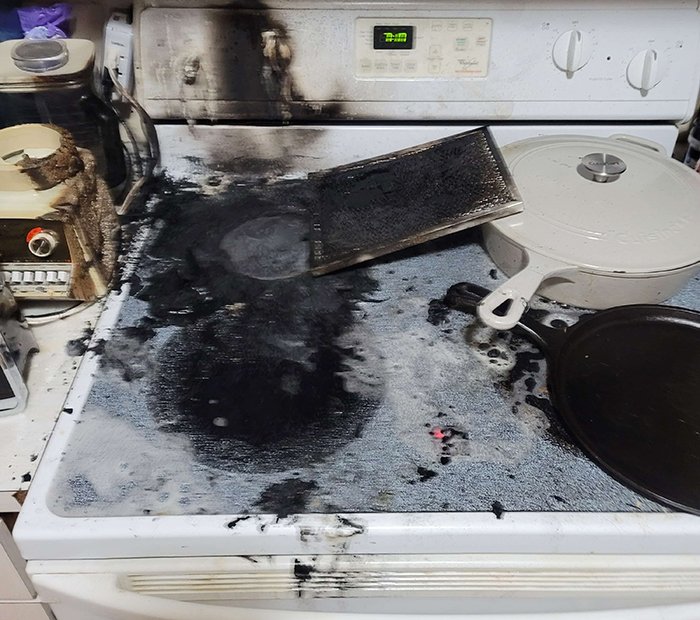 Burned stove and soot-covered kitchen after guy’s heroic actions, highlighting aftermath and being single is not the problem.