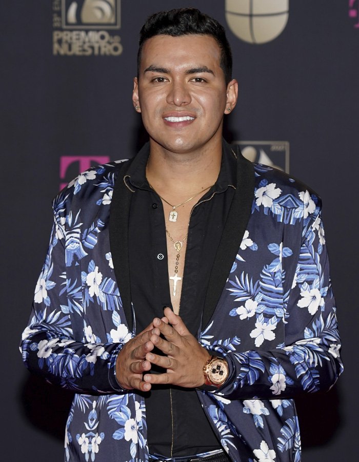 Famous singer wearing floral suit and gold accessories posing at an award event before tragic plane crash.