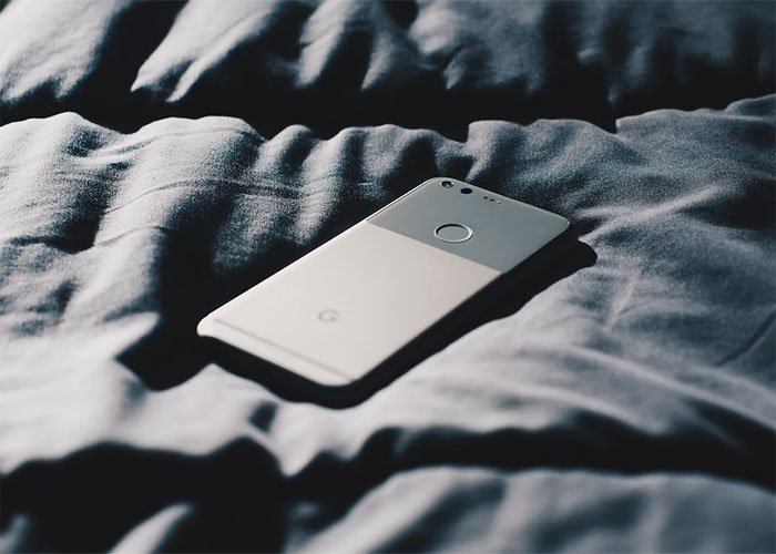 Smartphone resting on wrinkled dark fabric, symbolizing a boss calling HR about employee work outside office hours.