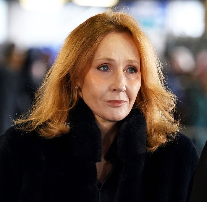 J.K. Rowling at an event, wearing a black coat, with serious expression amid media coverage of trans chef controversy.