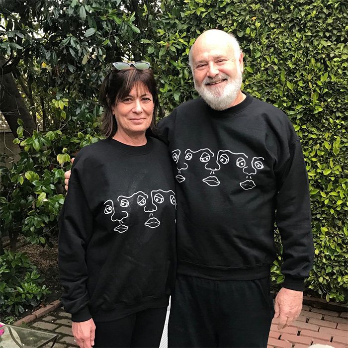 Nick Reiner’s family posing together outdoors, wearing matching black sweatshirts with abstract face designs.