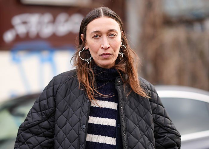 Woman wearing a black quilted jacket and striped sweater, involved in sister of Nicola Peltz's ex story after Brooklyn Beckham rant.