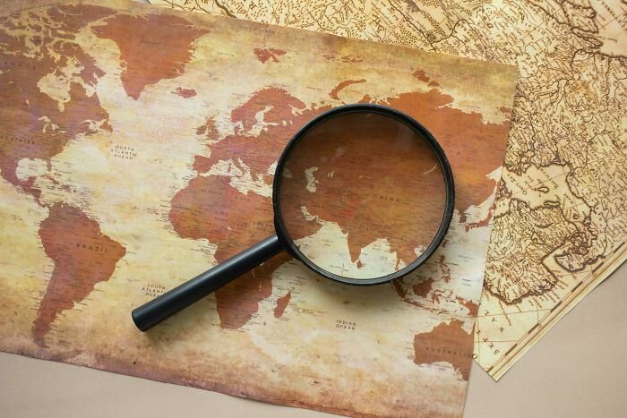 Vintage world map with a magnifying glass focusing on countries, illustrating a geography A to Z test challenge.