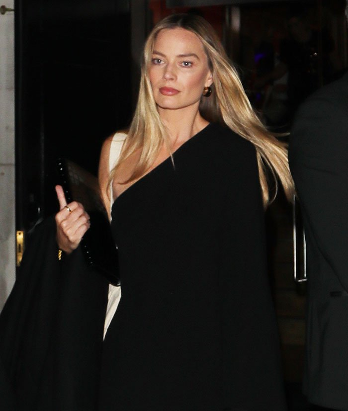Margot Robbie in a black outfit walking at night, related to her underwater cover shoot brutally roasted online.