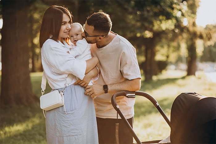 Young parents outdoors with their baby near a stroller, highlighting concerns about grandchild safety and babysitting trust.