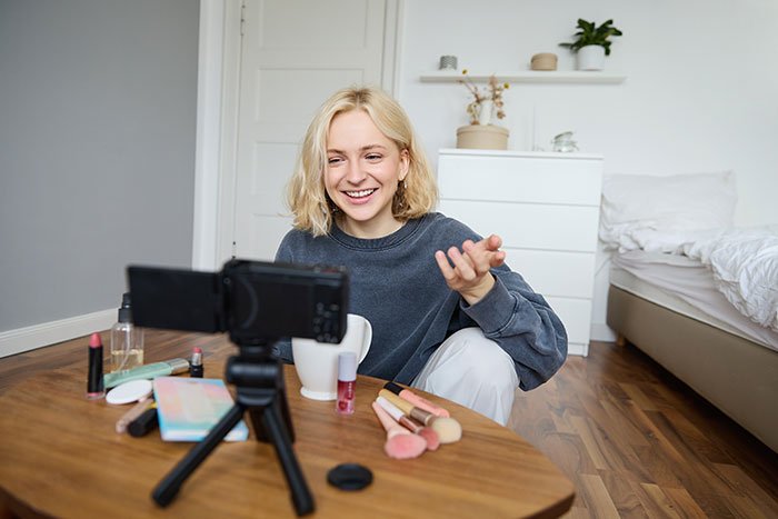 Young woman creating social media content at home, surprised by consequences after putting coworker on blast online.