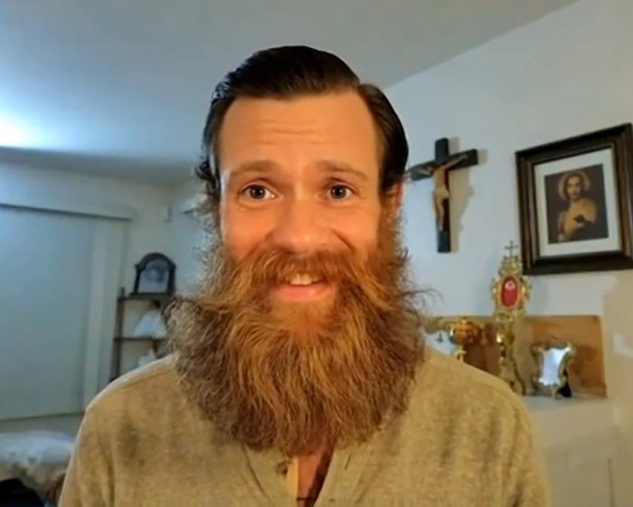 Former Little Rascals star with a long beard in a room with religious items, reflecting Catholic extremist lifestyle.