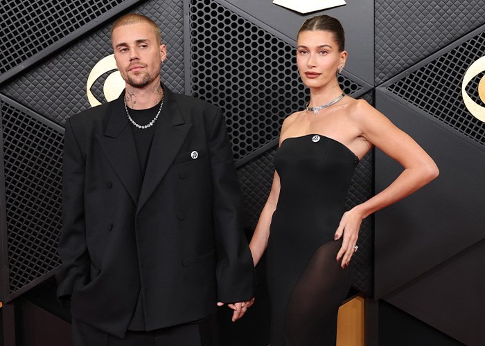 Justin Bieber and partner wearing black, posing on the red carpet as body language expert decodes tense behavior.