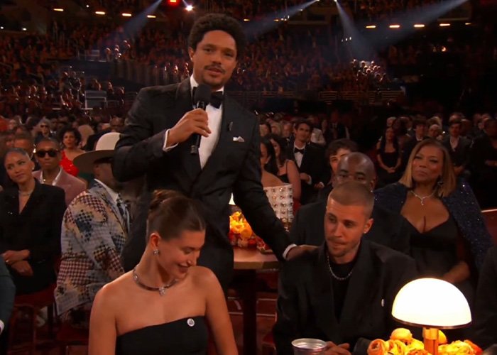 Trevor Noah in tuxedo speaking with Justin Bieber and a woman seated, capturing body language expert analysis moment.