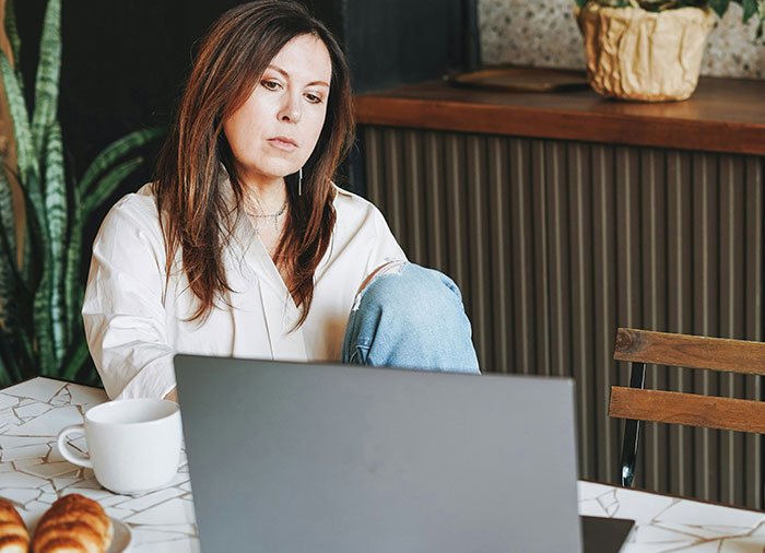 Woman sharing struggles with husband leaving and coming back, receiving a reality check while sitting at a table with a laptop.