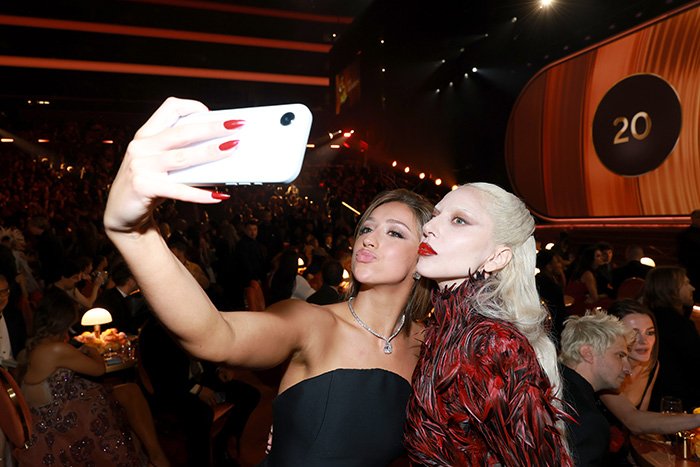 Two women at a Grammy event taking a selfie, highlighting the Grammy seatfiller rules and audience atmosphere.