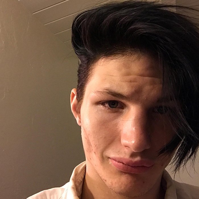 Young man with dark hair in low light, conveying emotions linked to horrifying exchange between young parents after baby's passing