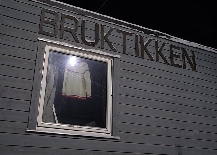 Exterior of a gray building with a window showing a sweater, highlighting life on the world’s darkest island.