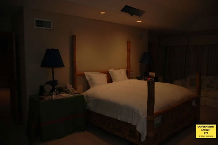 Dimly lit hotel room with a bed and side table, related to exotic dancer allegations against Epstein and Ex-Prince Andrew.